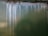 The image features a green metallic surface with noticeable streaks of rust and white corrosion lines descending vertically. The surface texture is rough, and the corroded areas display a contrast between the dark rust and the lighter spots.