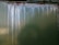 The image features a green metallic surface with noticeable streaks of rust and white corrosion lines descending vertically. The surface texture is rough, and the corroded areas display a contrast between the dark rust and the lighter spots.