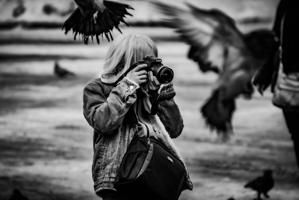 a woman taking a picture of a bird with a camera