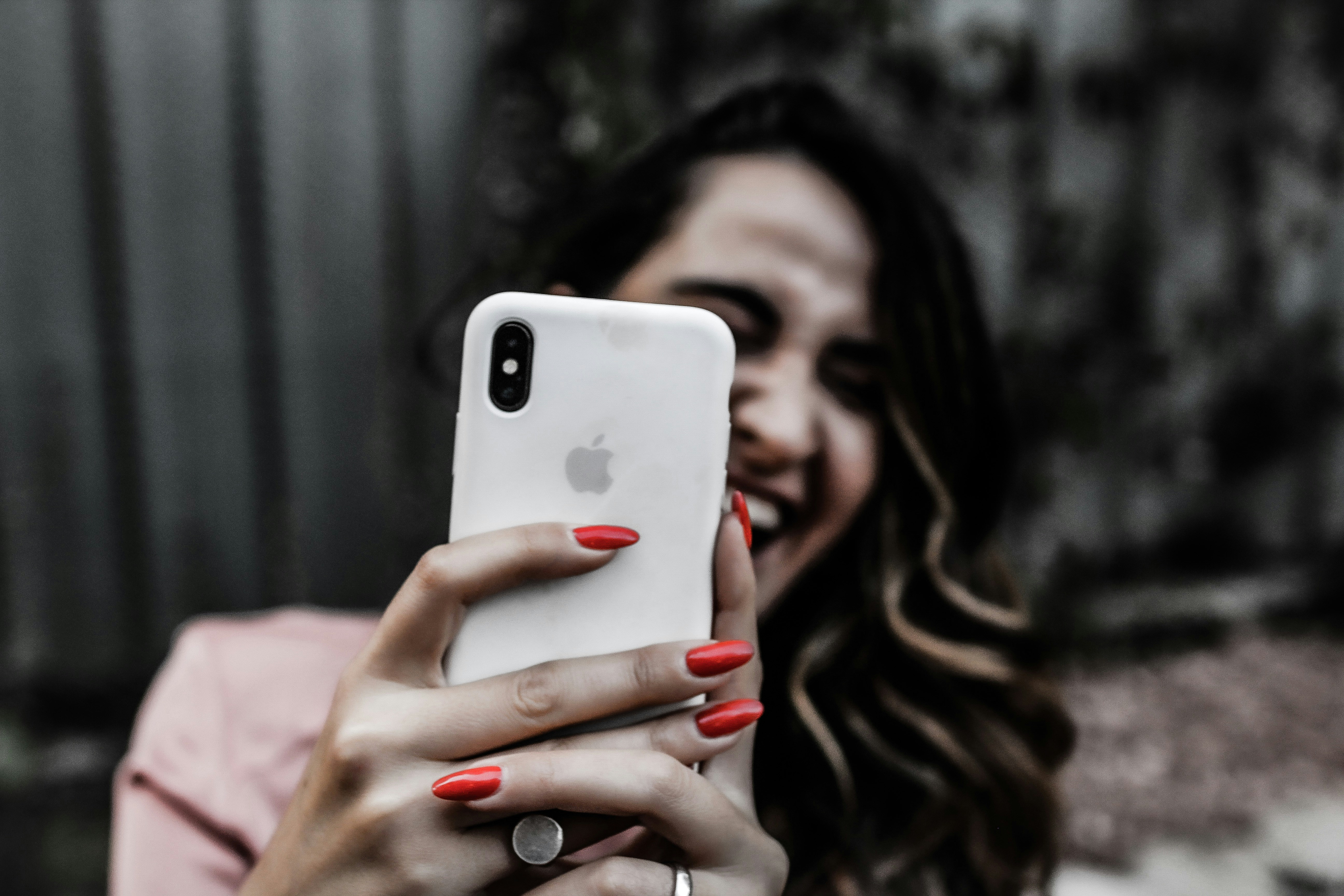 Woman with red nails holding iPhone while laughing