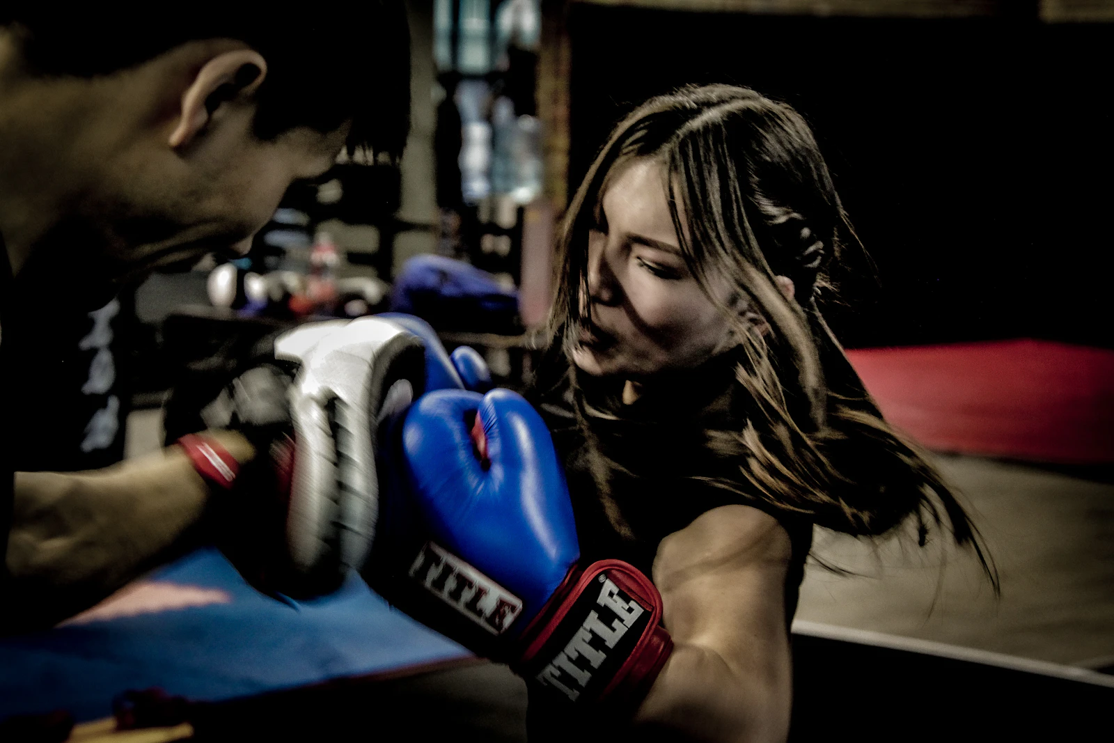 Two people training on pads in a boxing class