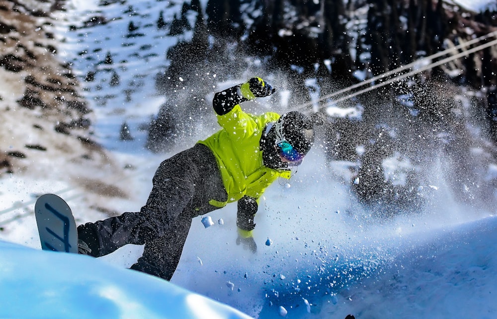 a man riding a snowboard down the side of a snow covered slope