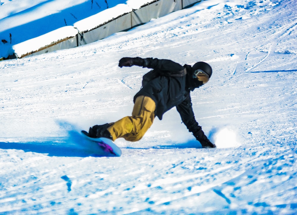 a man riding a snowboard down a snow covered slope