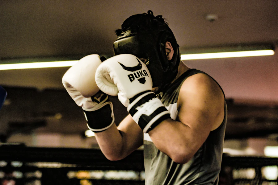 Pugilista com capacete e luvas em posição de guarda