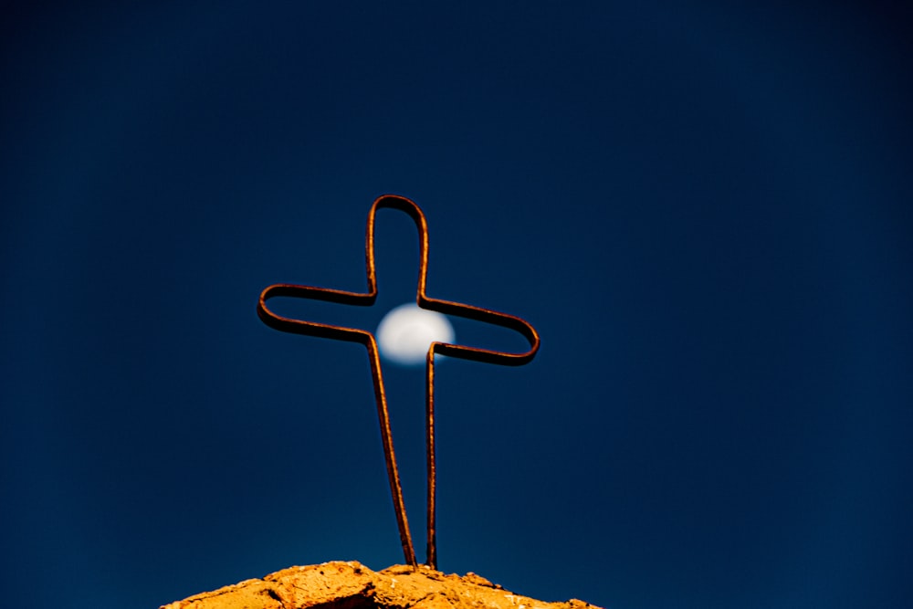 Una croce sulla cima di una collina con una luna sullo sfondo