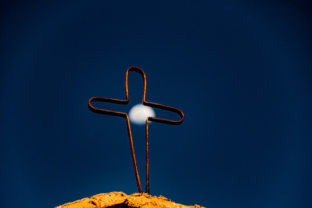Una cruz en la cima de una colina con una luna en el fondo