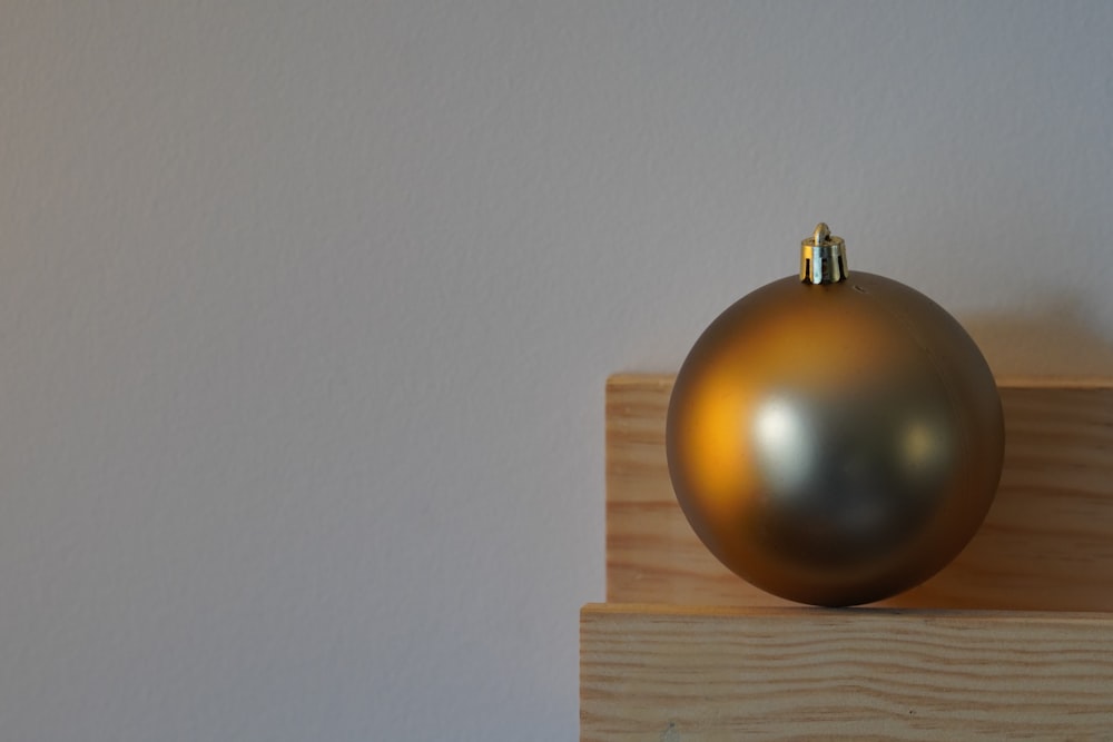 a shiny gold ball sitting on top of a wooden block