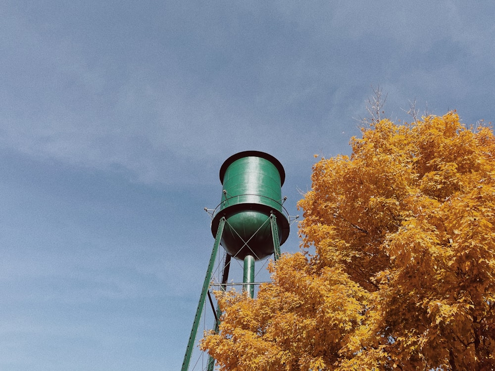 a tall green water tower next to a tree