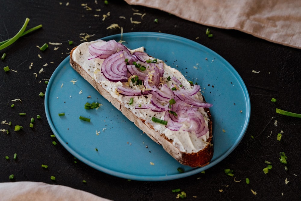 a sandwich on a blue plate topped with onions