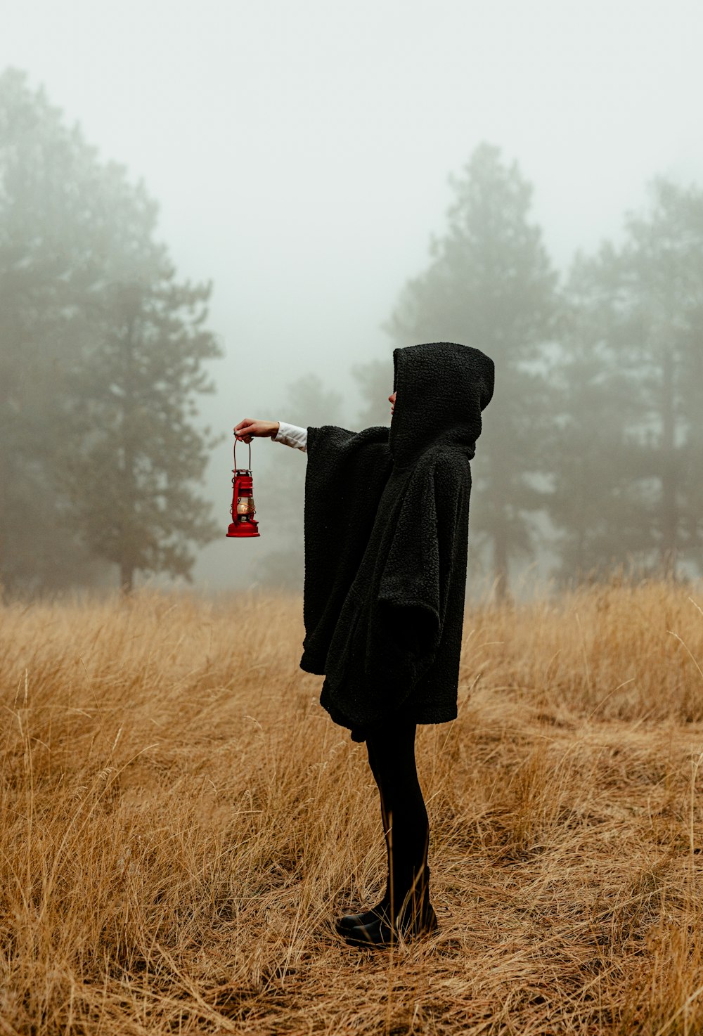 a person in a hooded jacket holding a red bell