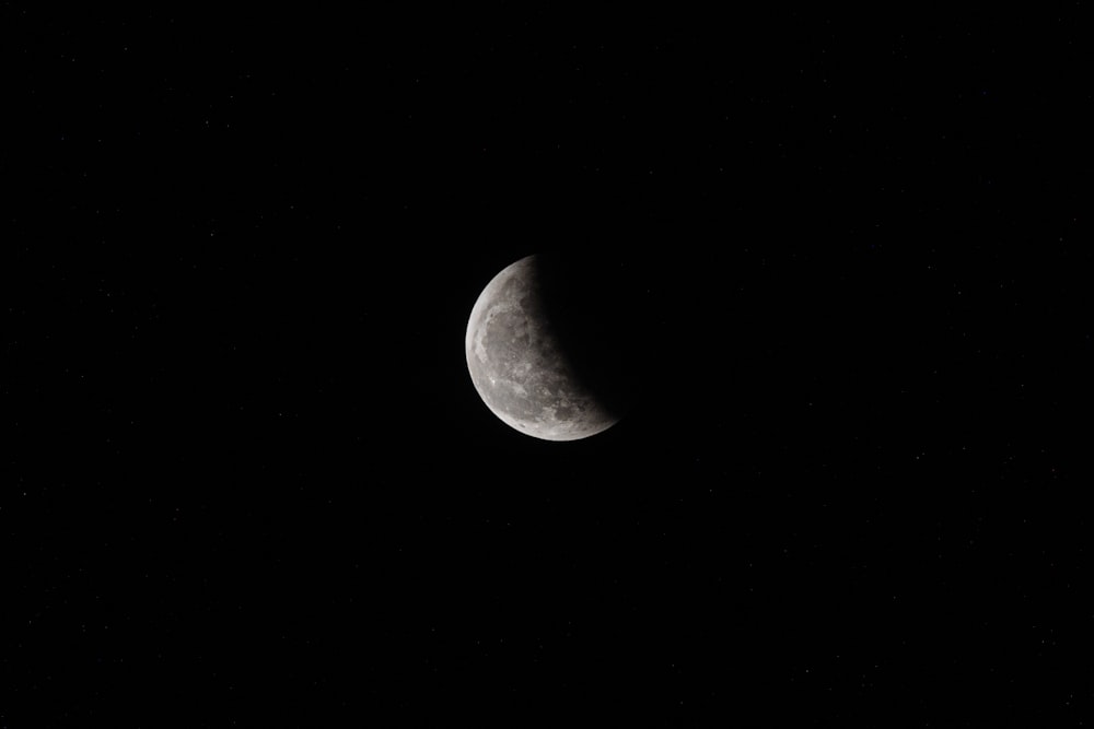 a half moon is seen in the dark sky