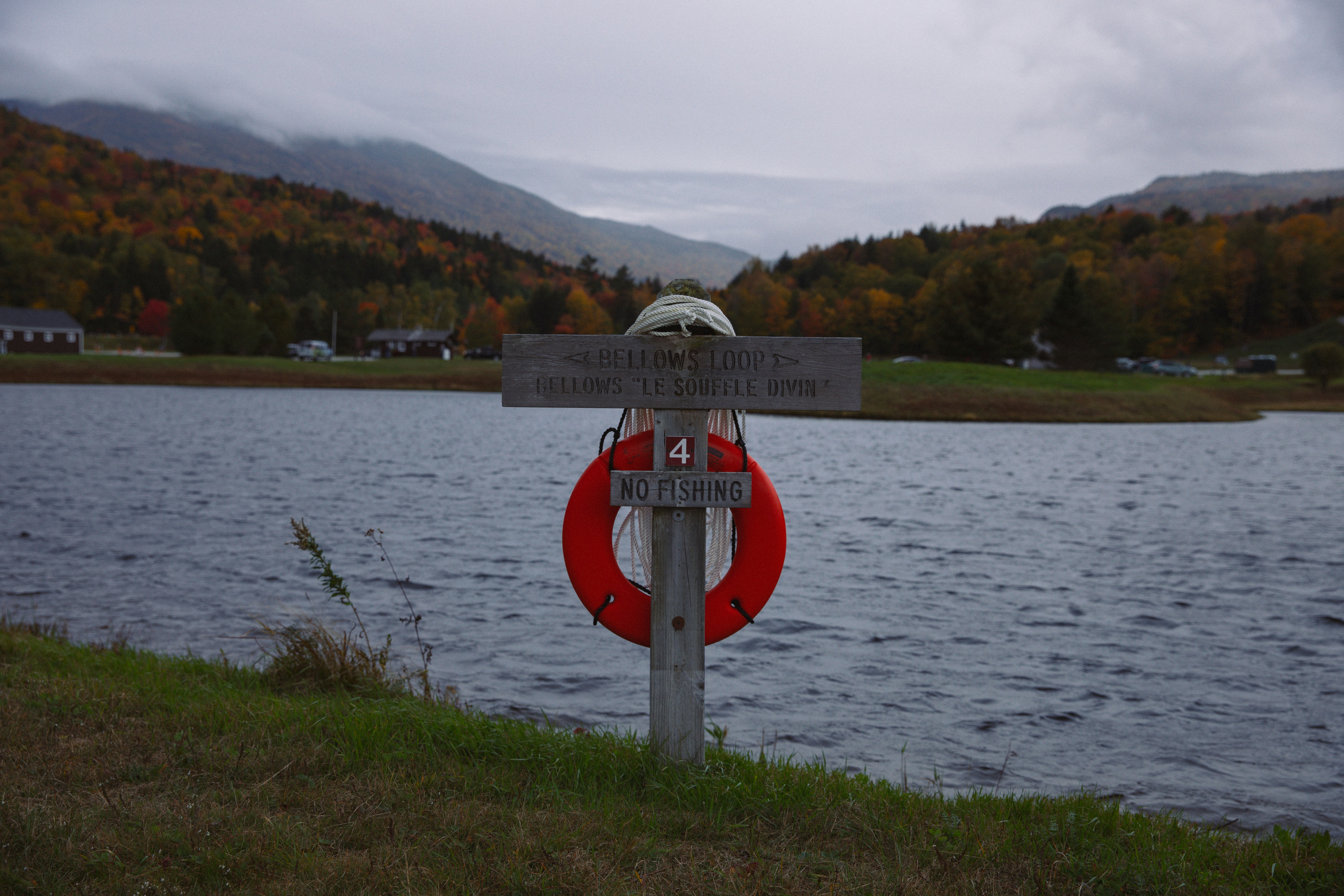 a red life preserver sitting on the side of a lake
