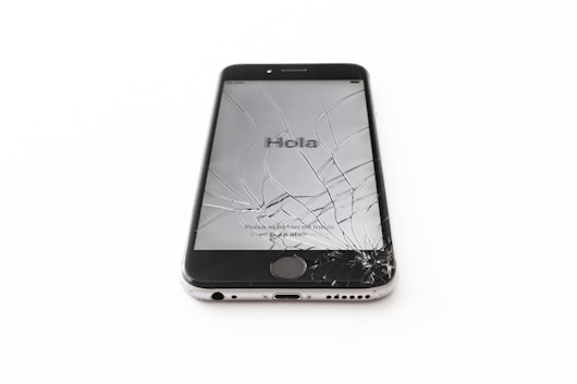an iphone with a cracked screen on a white surface