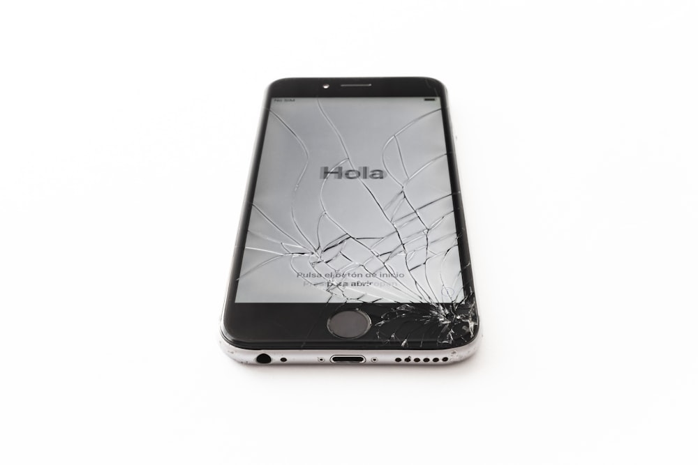 Un iPhone con una pantalla agrietada sobre una superficie blanca