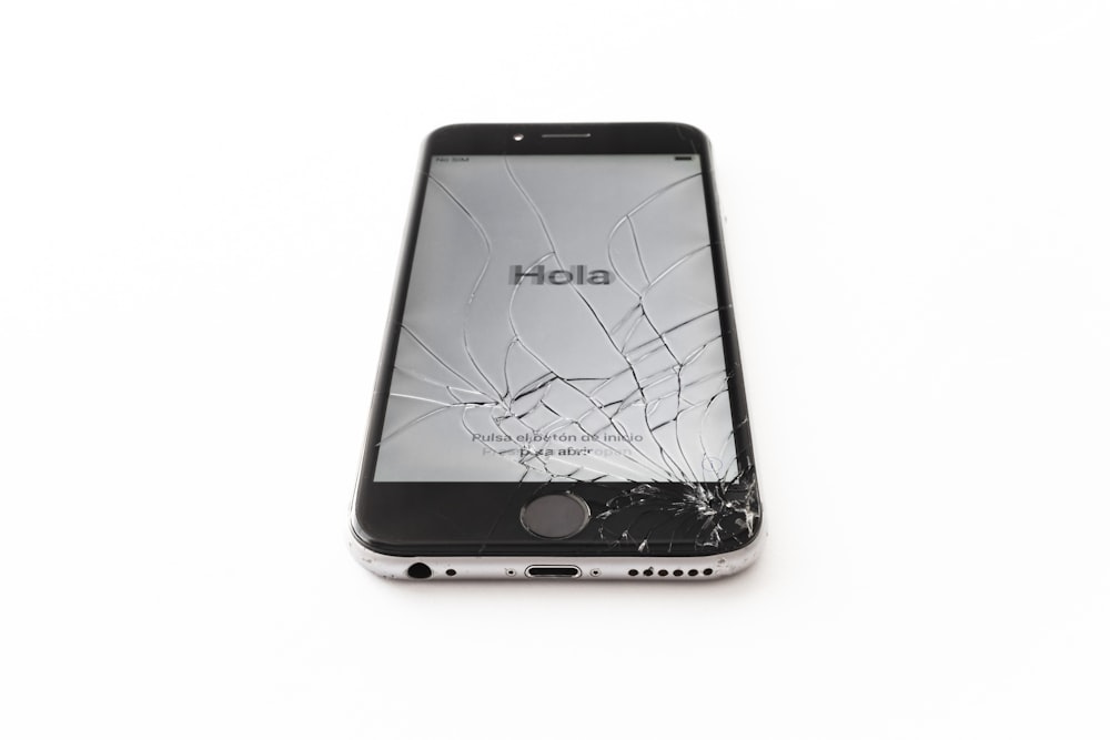 an iphone with a cracked screen on a white surface