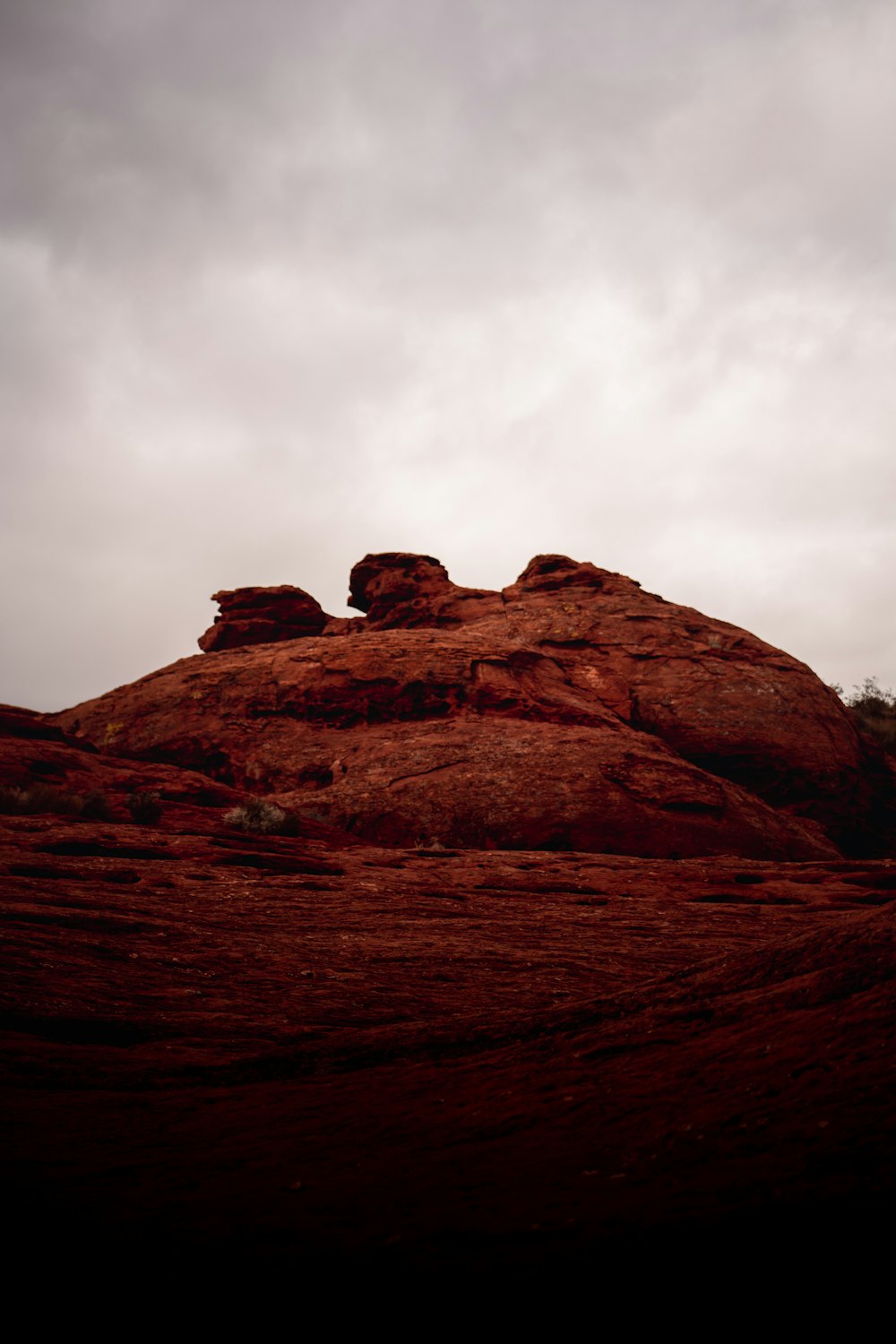 a red rock formation with a cloudy sky in the background