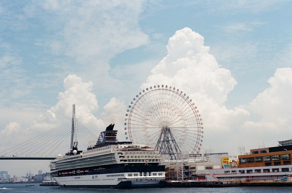 a cruise ship docked in a harbor with a ferris wheel in the background
