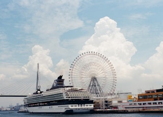 a cruise ship docked in a harbor with a ferris wheel in the background