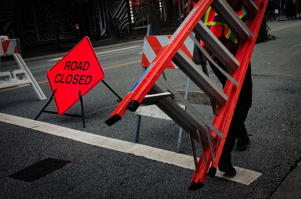 a road closed sign next to a ladder