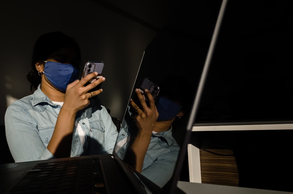 a woman in a blue shirt is holding a cell phone