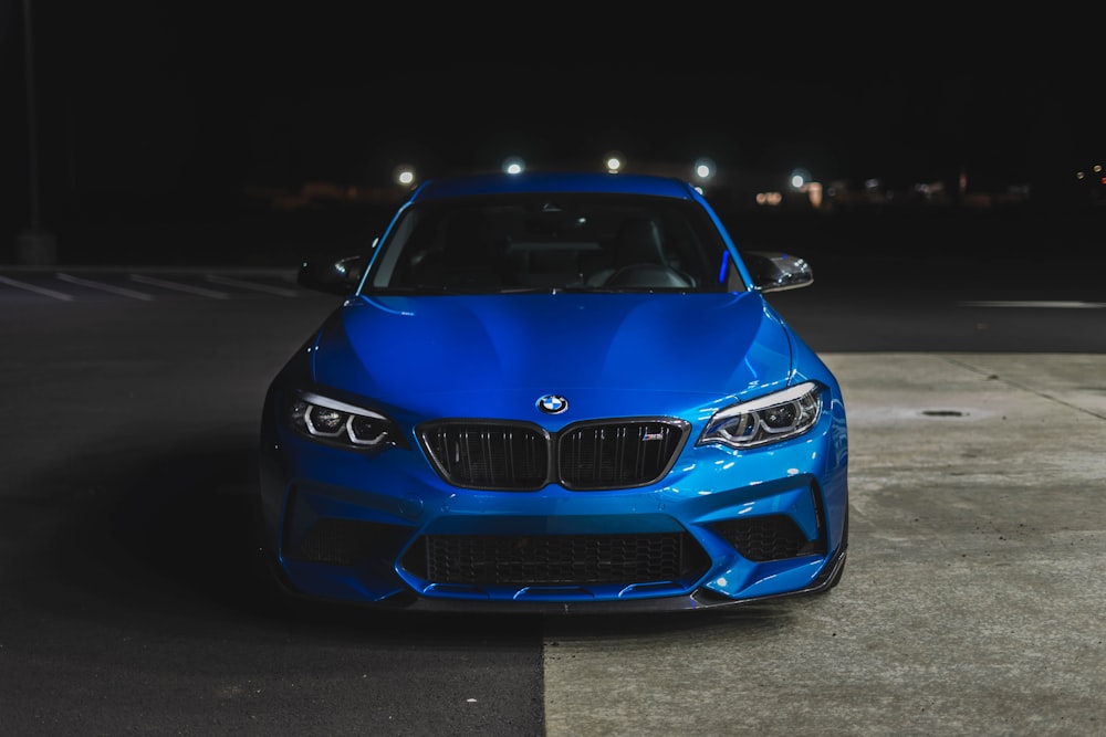 a blue car parked in a parking lot at night