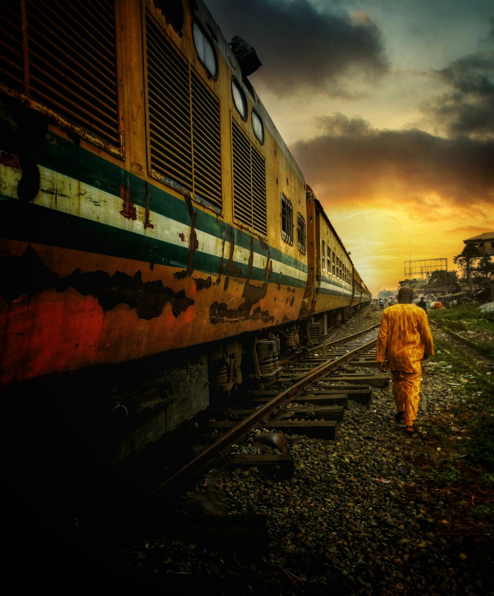a person in a yellow outfit walking on train tracks