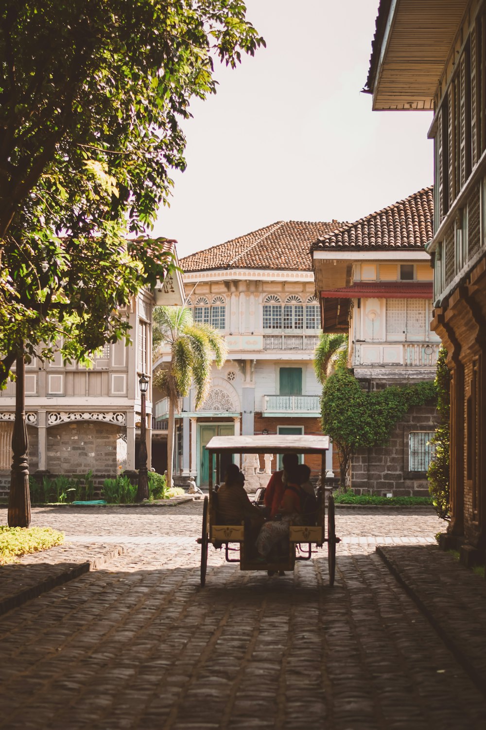 two people sitting in a cart on a cobblestone street