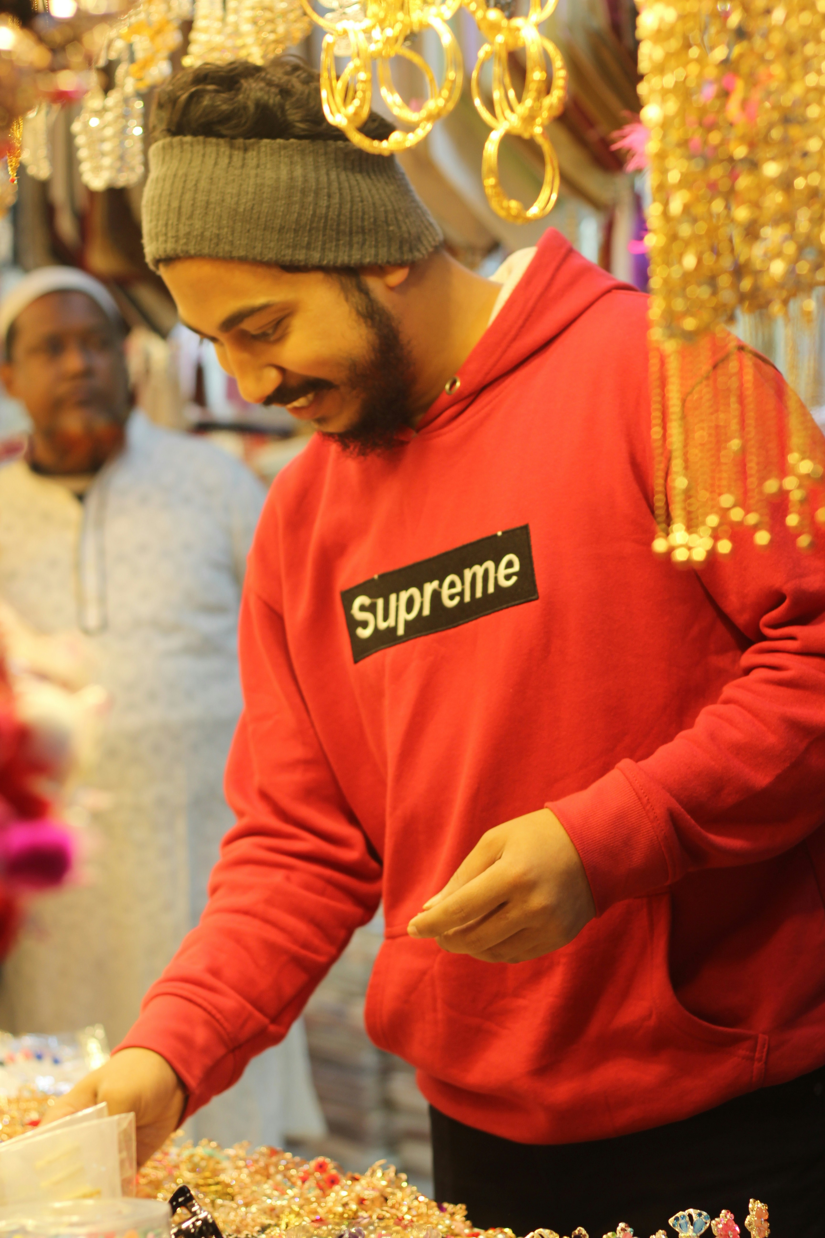 a man in a red hoodie cutting a cake