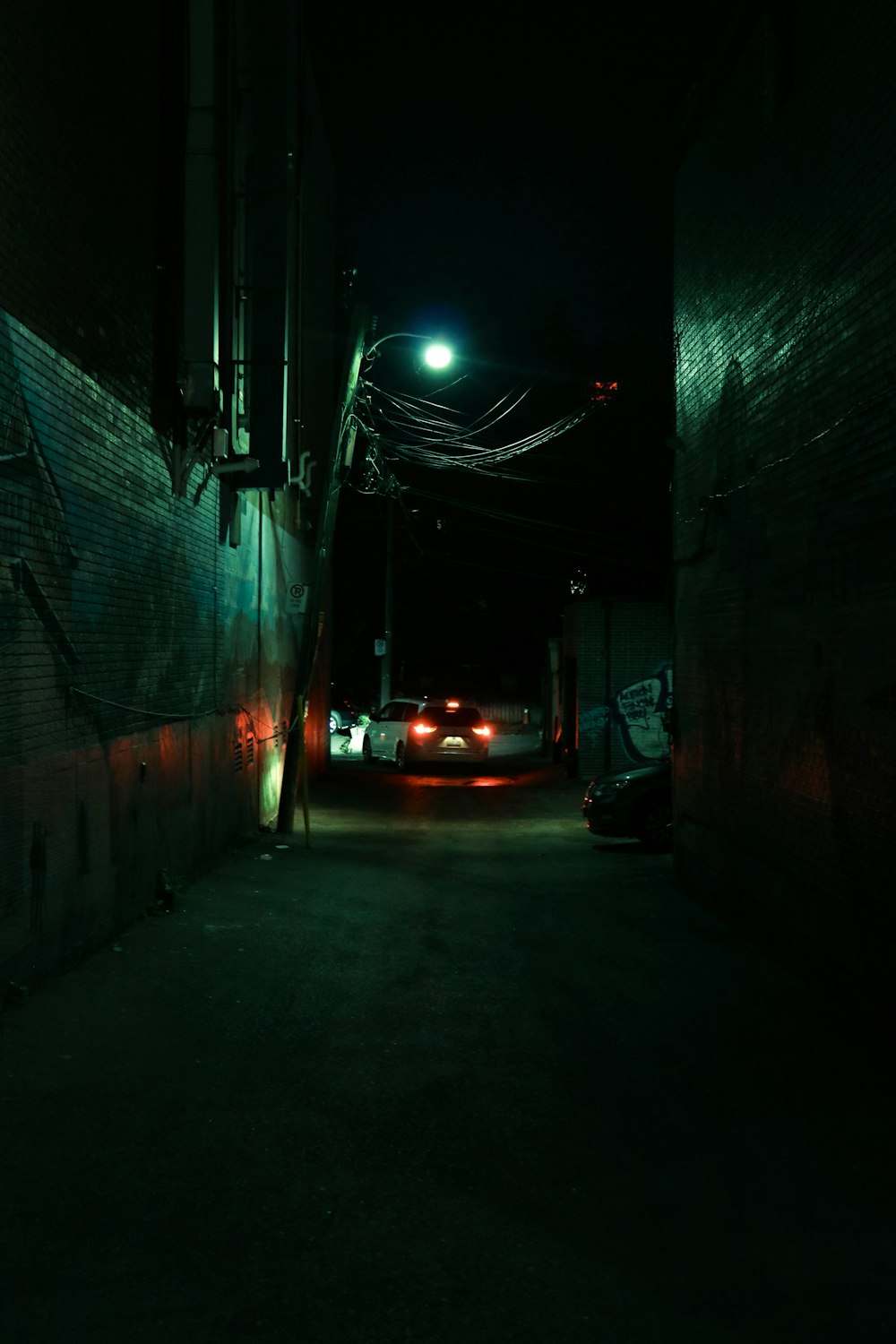 a dark alley at night with cars parked on the side