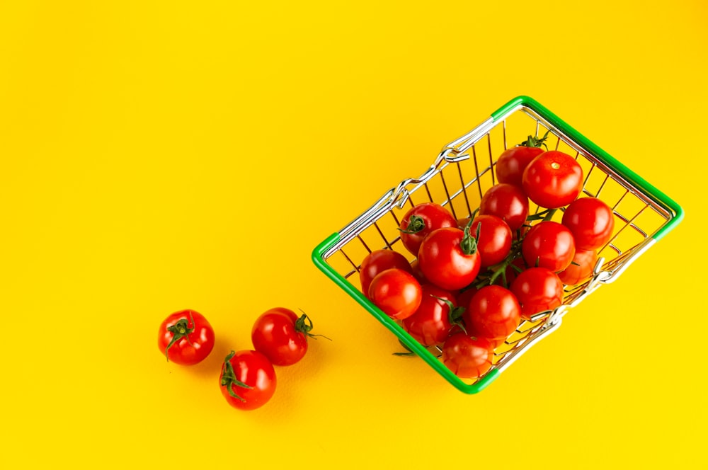 Una canasta de tomates sobre un fondo amarillo