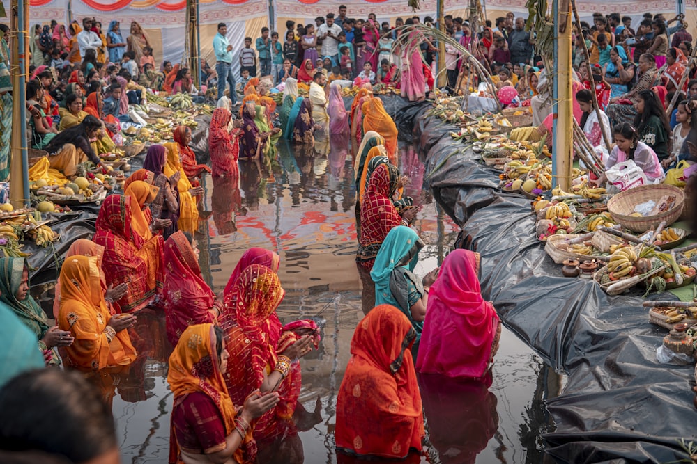 a group of women in colorful saris standing around a table full of food