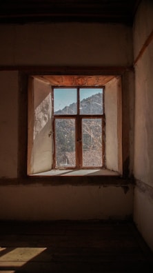 Rustic window framed by colorful patterned drapes in a sunlit room.