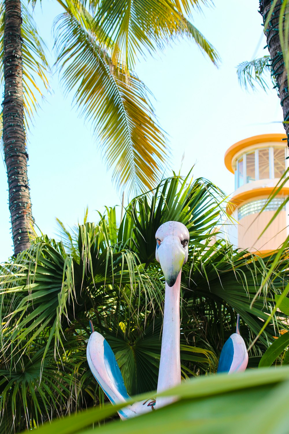 a pink flamingo statue in front of palm trees