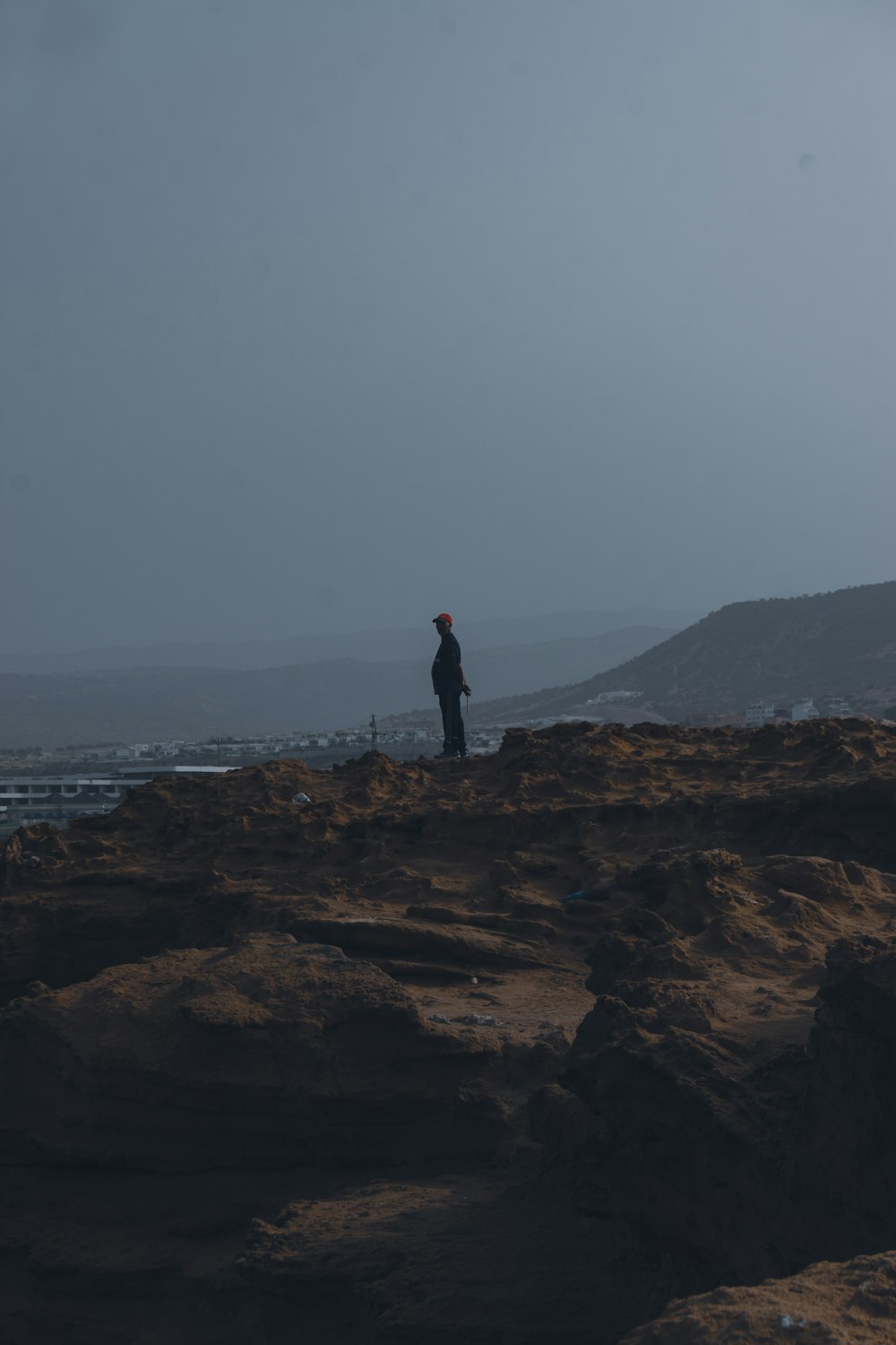 a man standing on top of a rocky cliff next to the ocean