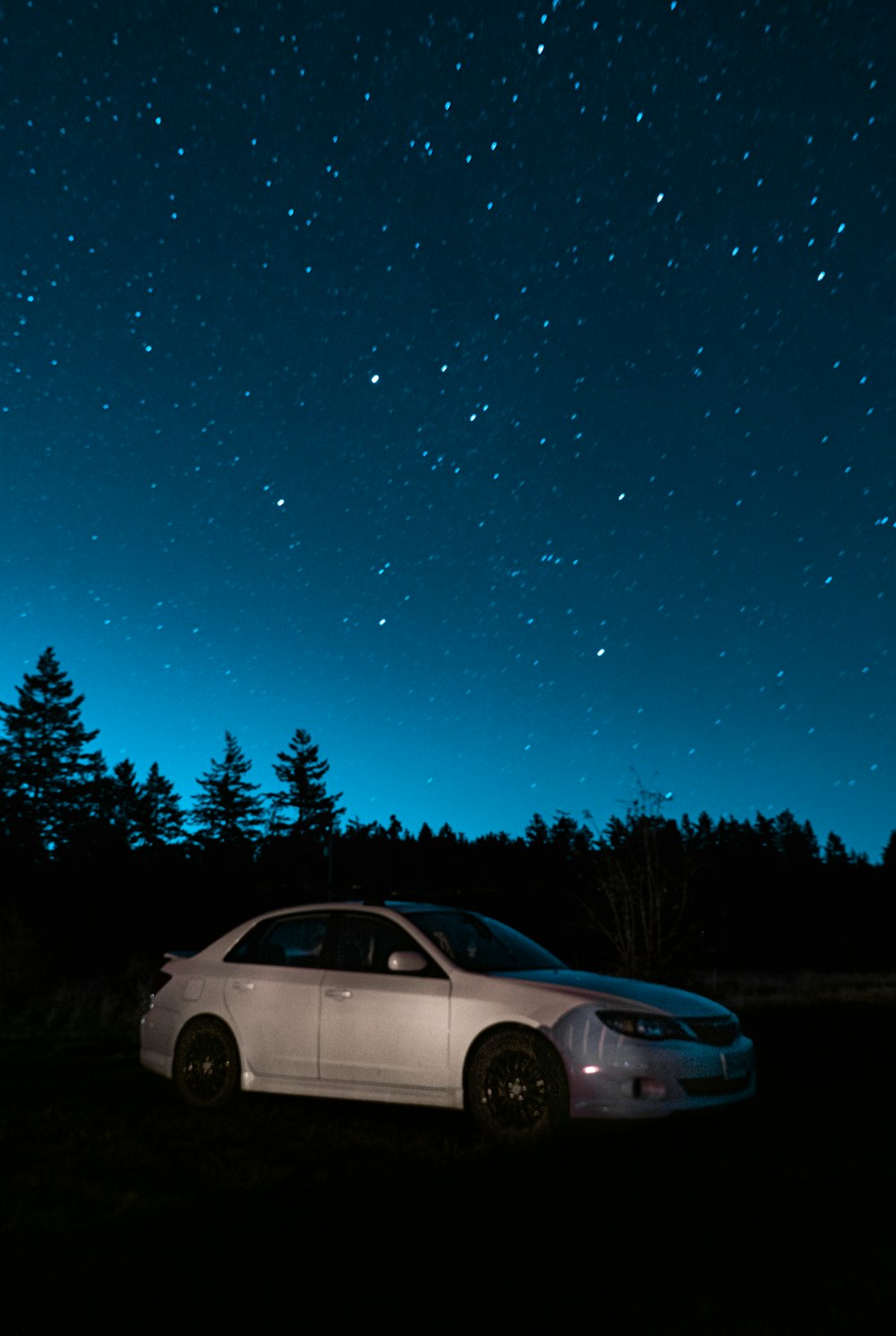 a car parked in a field at night under the stars