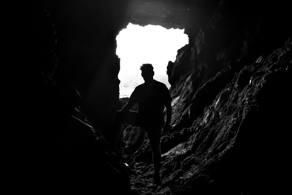 a man standing in a cave looking out at the ocean