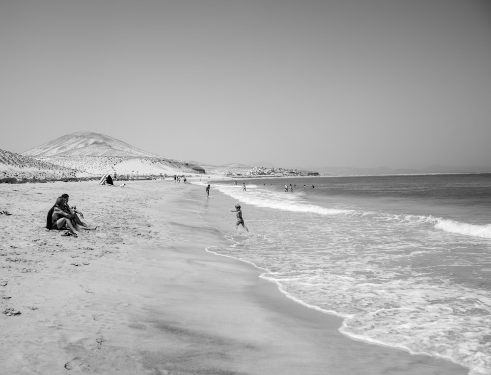 a group of people sitting on top of a sandy beach