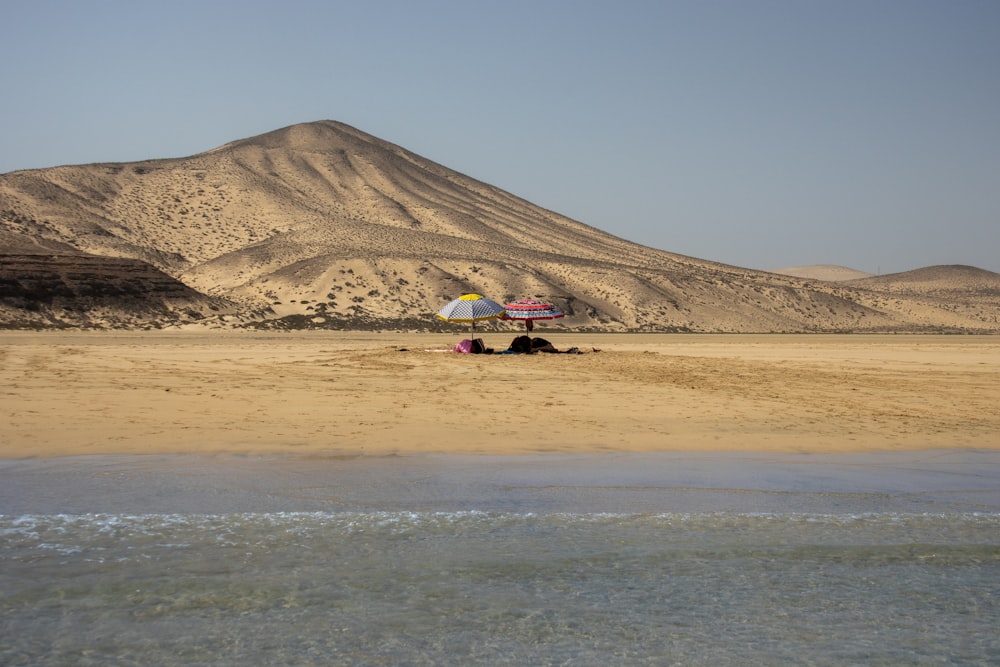 a plane sitting on the beach with a mountain in the background