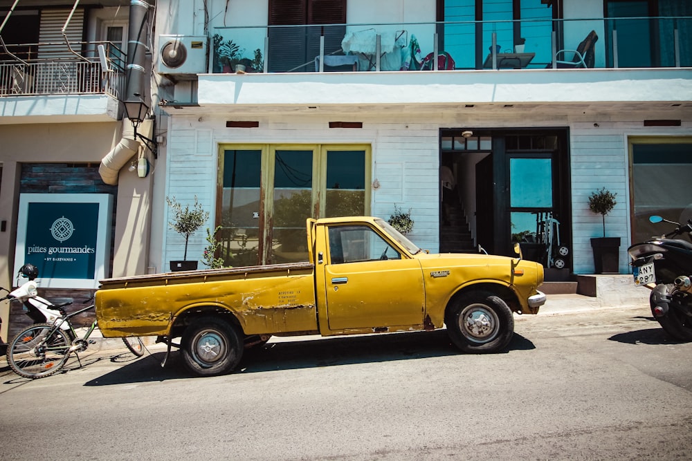a yellow pick up truck parked in front of a building