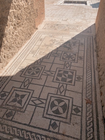 Close-up of a detailed stone mosaic pathway bordered by colorful seasonal flowers.