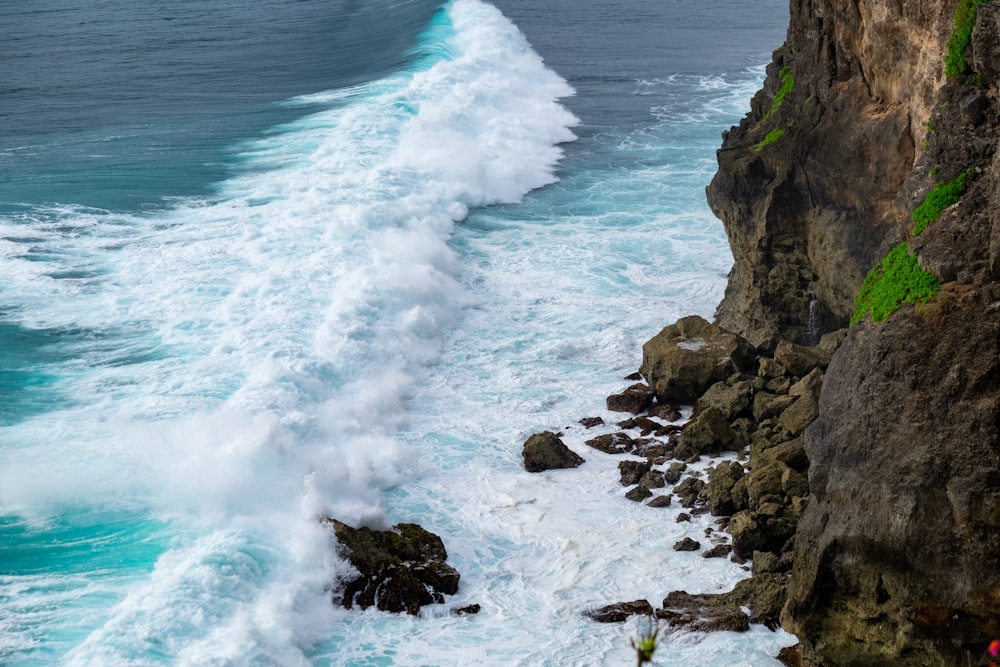 a large wave crashing into the shore of a cliff