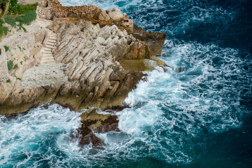 an aerial view of a rocky coastline with blue water
