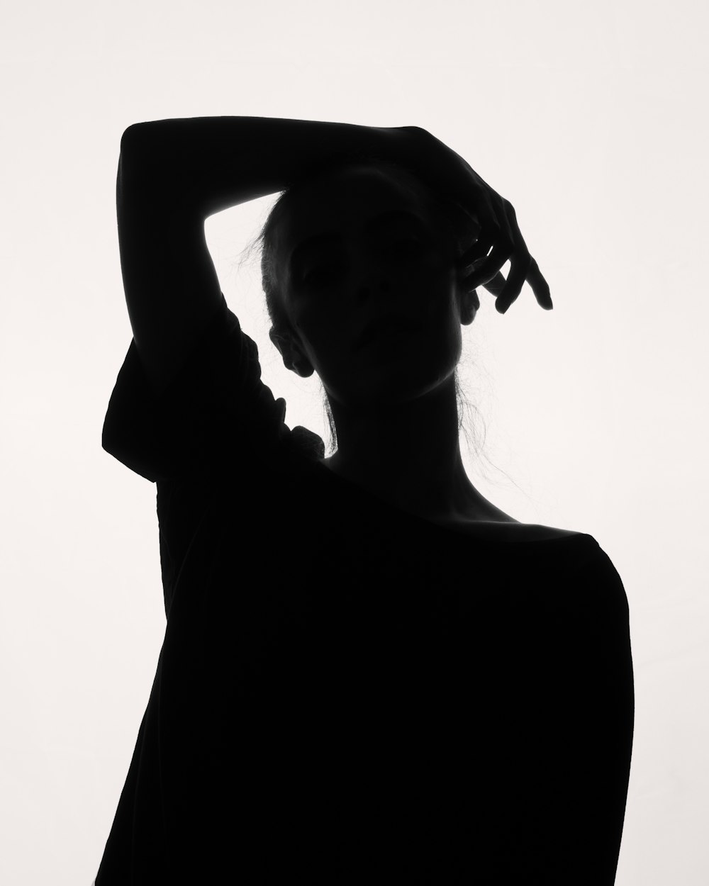 a black and white photo of a woman with her hands on her head