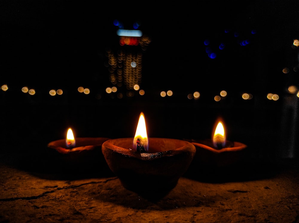 Trois bougies allumées assises dans un bol sur une table