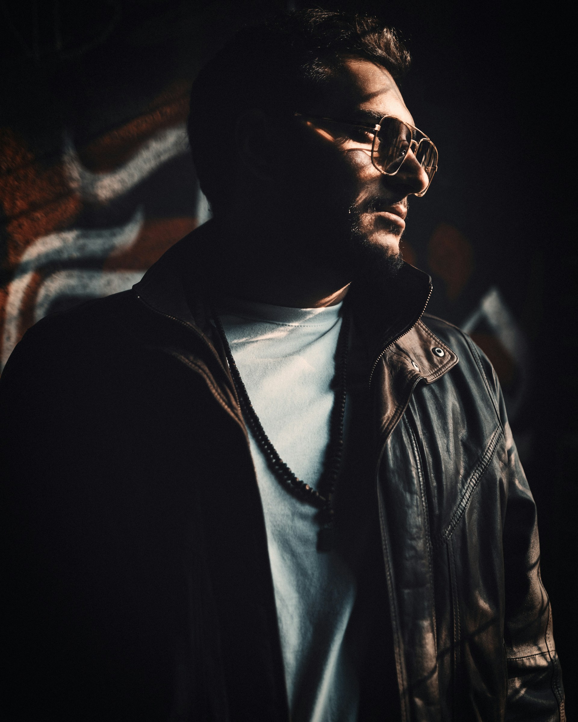 a man wearing glasses and a leather jacket