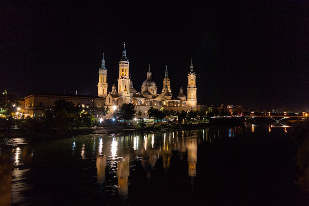 a large cathedral lit up at night over a body of water