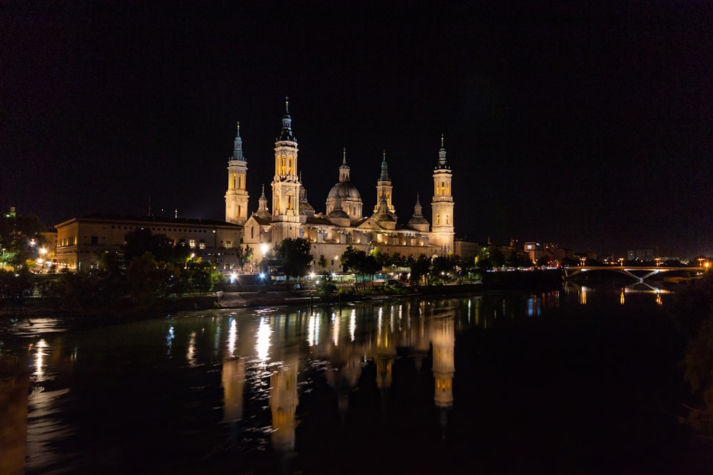 Una grande cattedrale illuminata di notte su uno specchio d'acqua