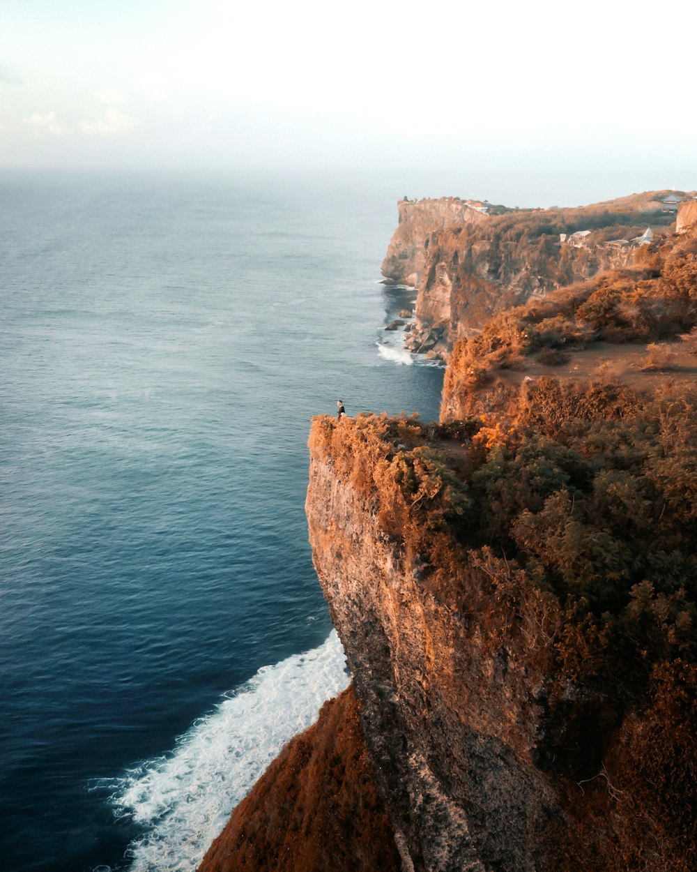 a cliff with a body of water in the background