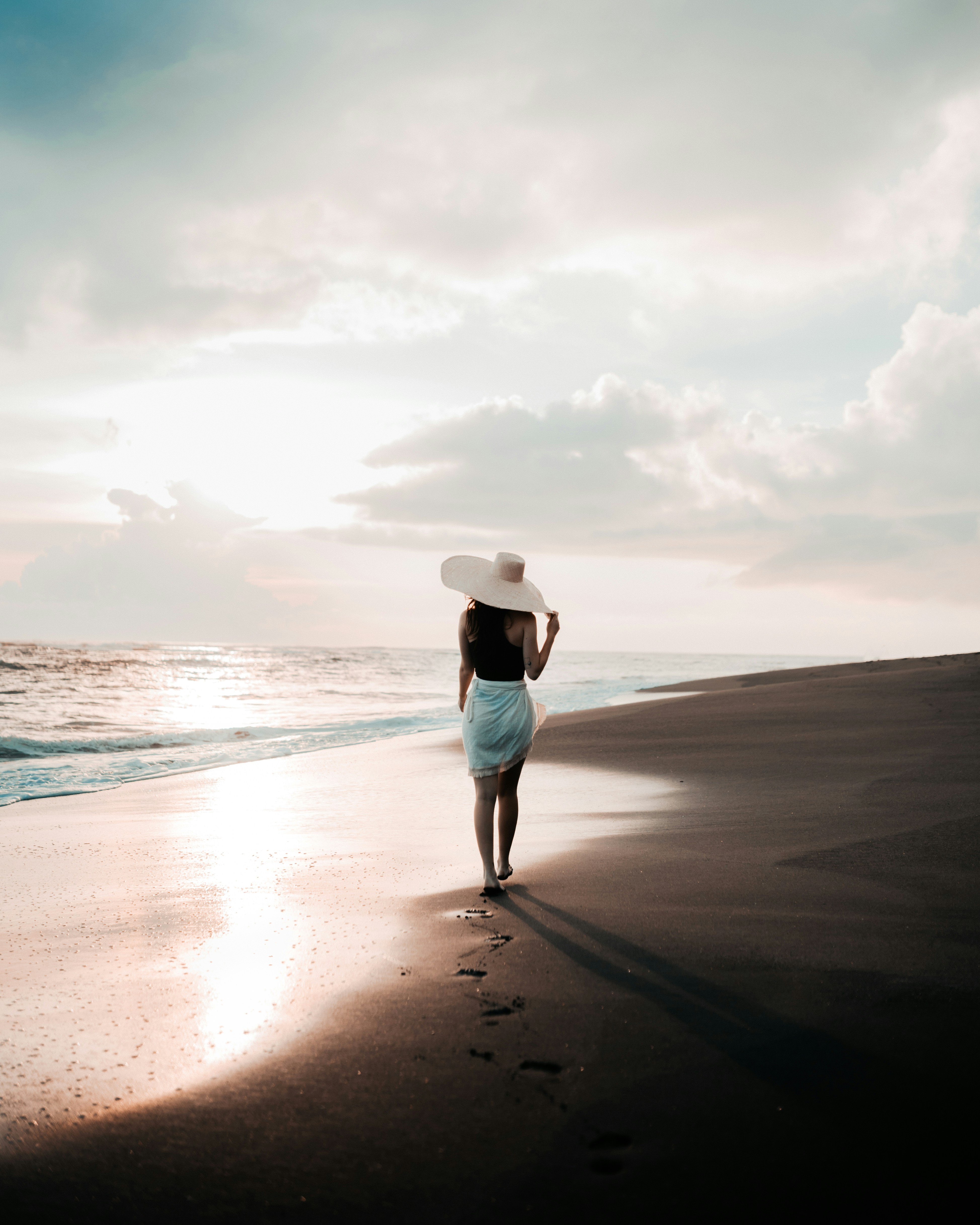 great photo recipe,how to photograph a walk through another world; a woman in a white hat walks along the beach