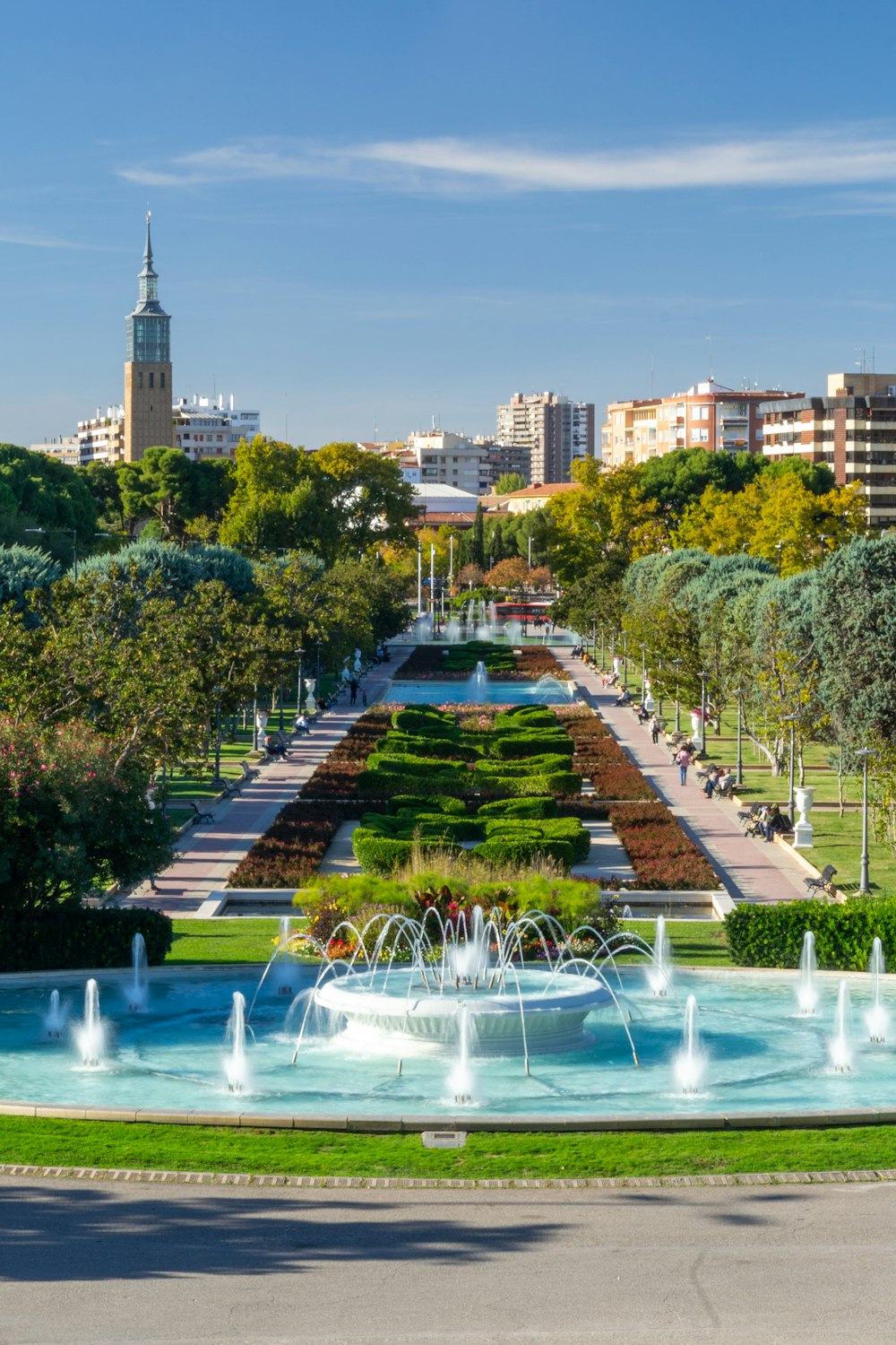a view of a park with a fountain and buildings in the background